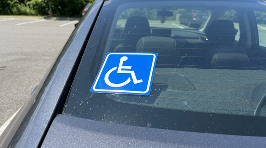 Autocollant handicap au symbole fauteuil roulant apposé sur la vitre arrière d’une voiture