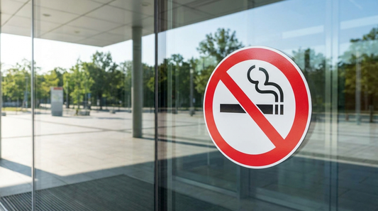 Panneau interdiction de fumer (cigarette barrée, rond rouge) sur la porte vitrée d'un établissement