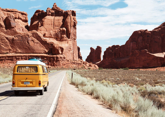 Van jaune vintage sur une route au milieu de paysages désertiques d'été