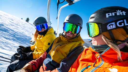 Casque de ski décoré de stickers posé sur un banc enneigé au pied des pistes