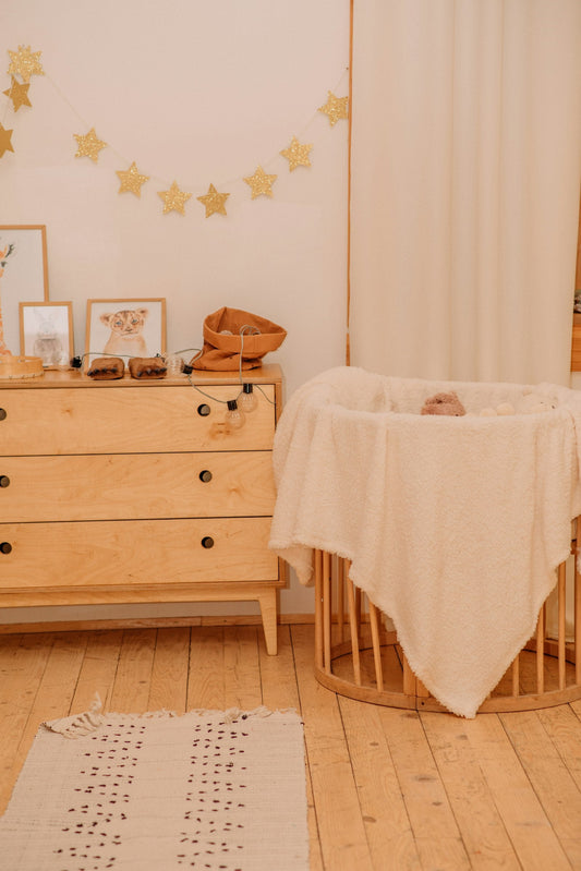 Coin de chambre d'enfant avec guirlande d'étoiles au mur, commode en bois et berceau