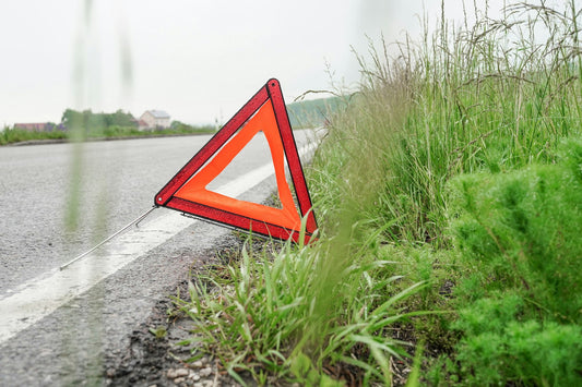 Triangle de présignalisation rouge déplié au bord de la chaussée sur une route de campagne