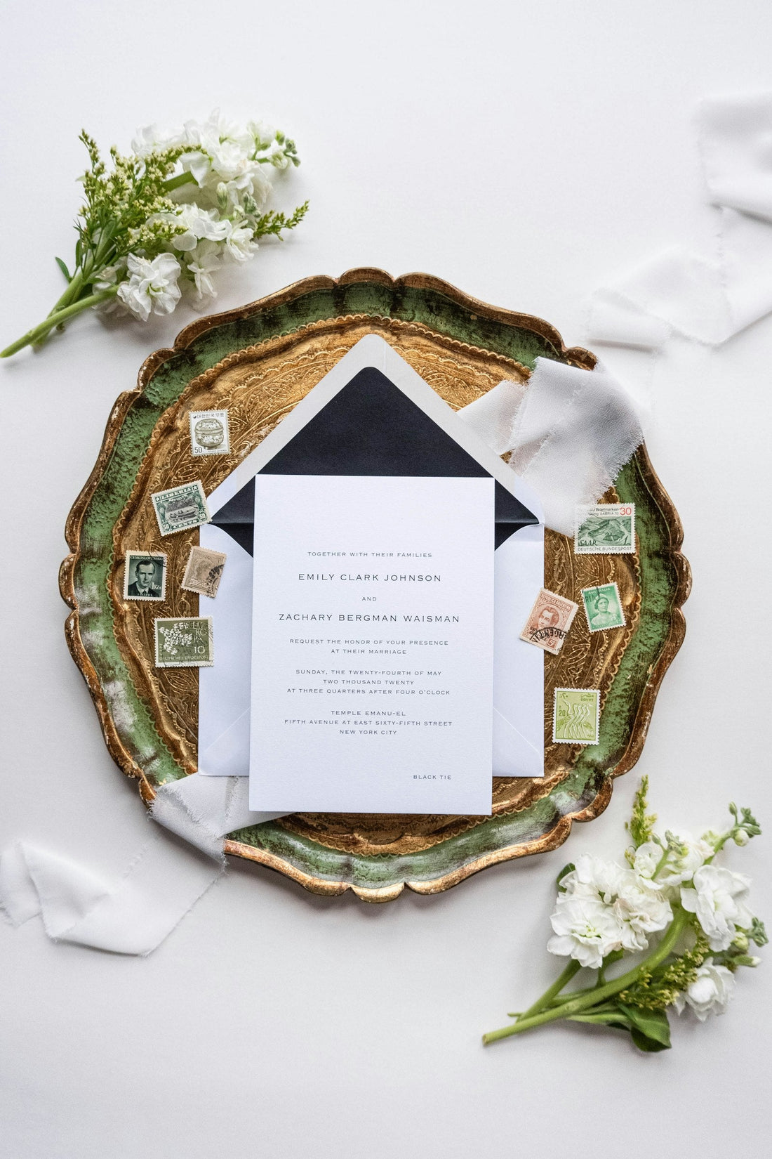 Flat-lay de papeterie de mariage : faire-part, enveloppe doublée, ruban et timbres anciens