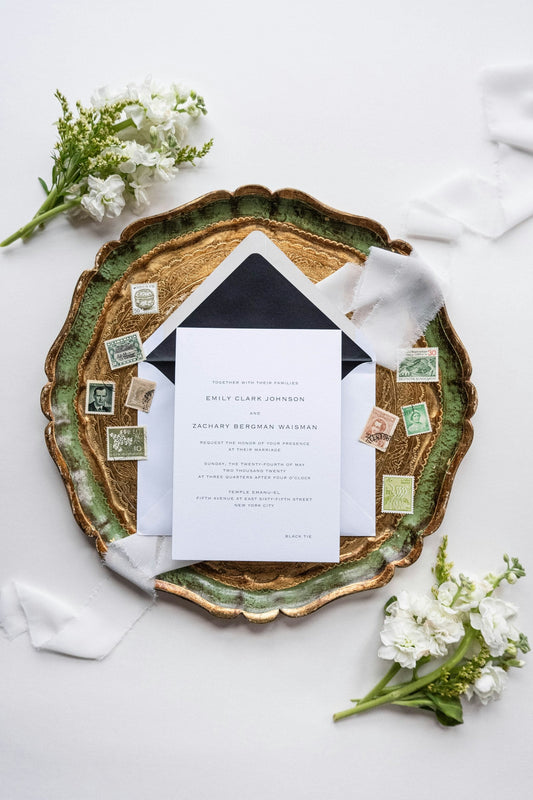 Flat-lay de papeterie de mariage : faire-part, enveloppe doublée, ruban et timbres anciens