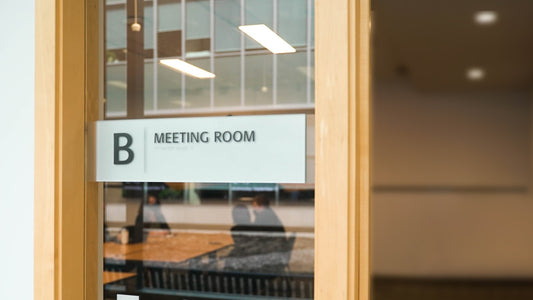 Plaque de porte en aluminium brossé gravée avec le nom et la fonction, fixée sur une porte de bureau moderne