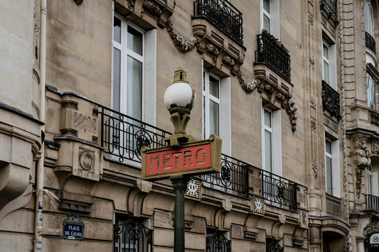 Façade haussmannienne parisienne avec une plaque de rue émaillée bleue « Place de l'Alma » et un mât Métro