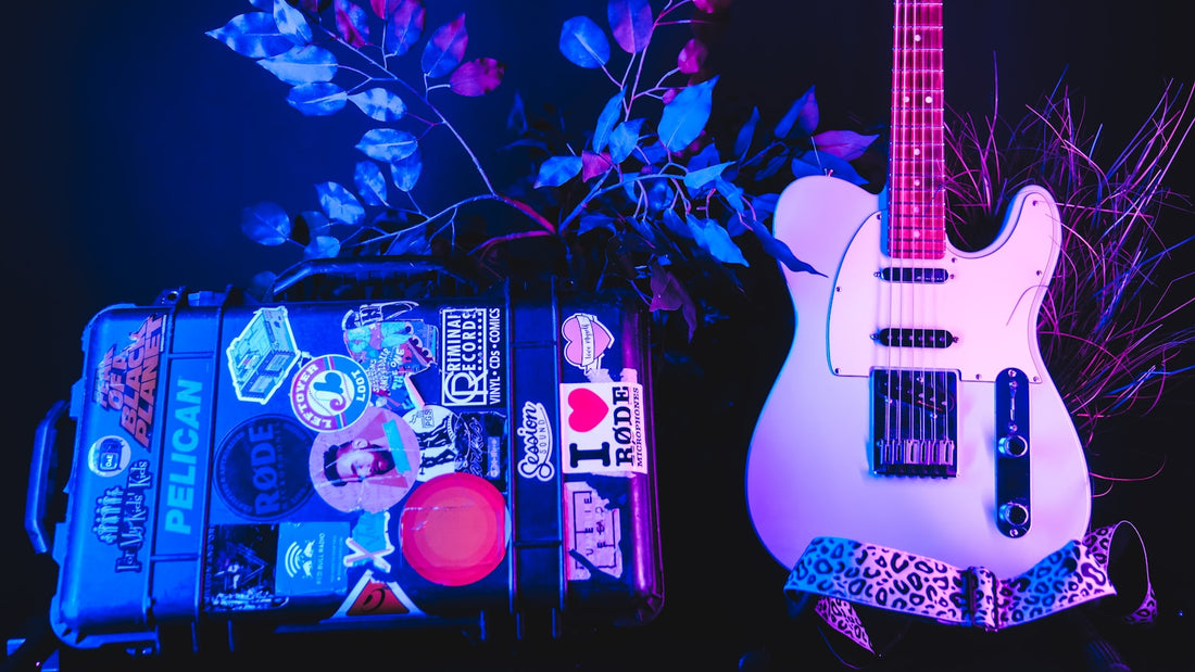 Étui rigide de guitare noir couvert d'autocollants, poignée et fermoirs visibles