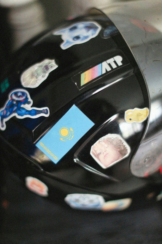 Casque de moto noir couvert d'autocollants variés, illustrant la personnalisation d'un casque de moto avec des autocollants.