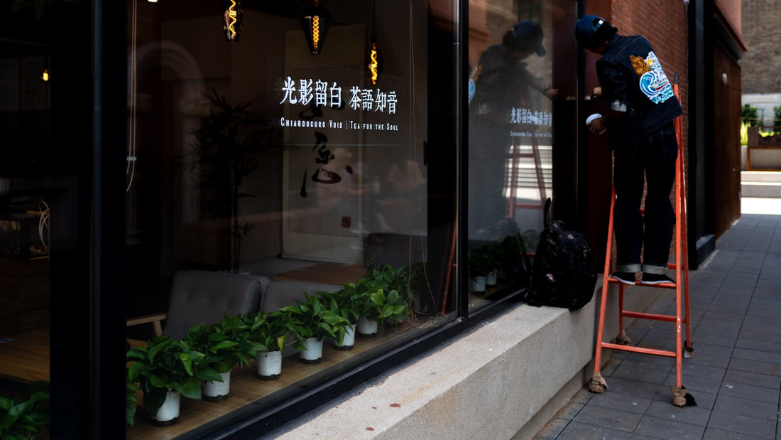 Marouflage d'un adhésif sur une vitrine à la raclette feutrée