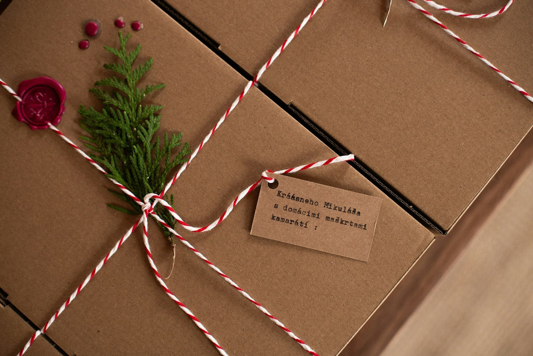 Coffret artisanal en carton kraft fermé d'une ficelle bicolore, d'un cachet de cire et d'une étiquette kraft, avec une branche de cèdre