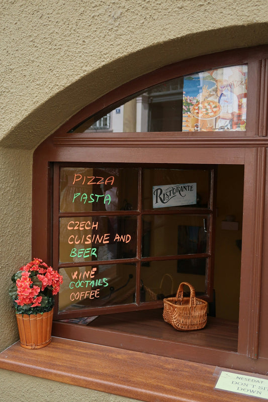 Vitrine de restaurant avec un menu manuscrit affiché sur la fenêtre, plats et boissons proposés visibles depuis la rue