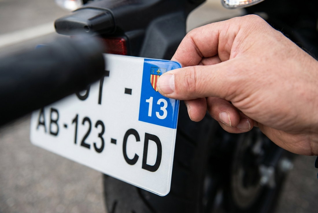 Pose d'un sticker département sur une plaque d'immatriculation moto au format 210 x 130 mm